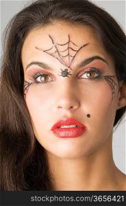 close up of young and nice brunette with spider web painted on face
