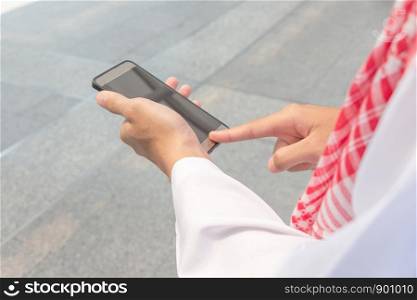 Close up of young Arab Middle Eastern Businessman using mobile smartphone blurry background.