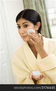 Close up of young Asian/Indian woman applying facial scrub.