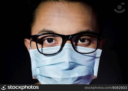 close up of young asian man wearing hygienic mask annd glasses with dark blackground
