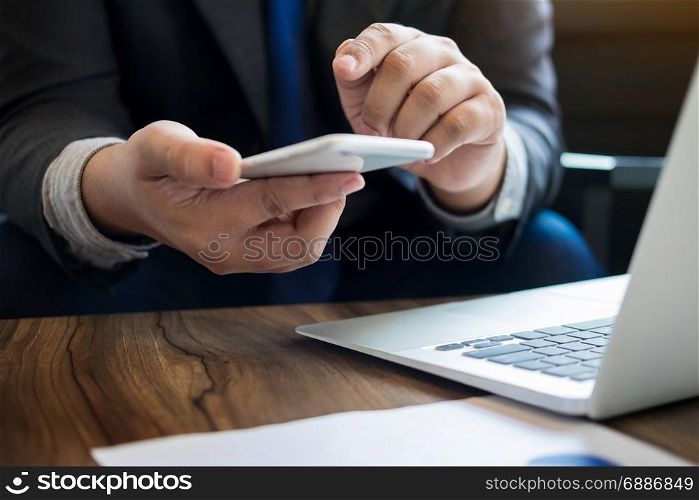Close up of young business man using mobile smart phone for working in his office