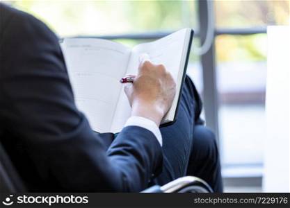 Close-up of young businessman working with read the note recorded in the business plan notebook In the office room copy space background.