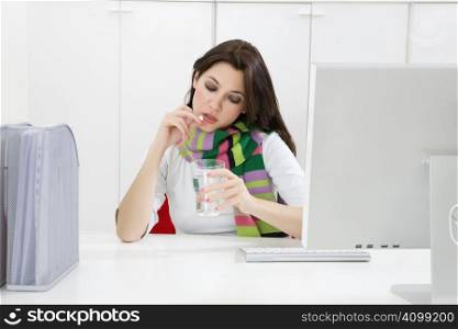 Close-up of young businesswoman putting pill in mouth in office