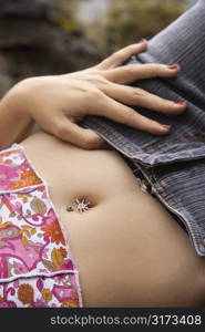 Close up of young Caucasian female lying down with hand on hip and bare midriff.