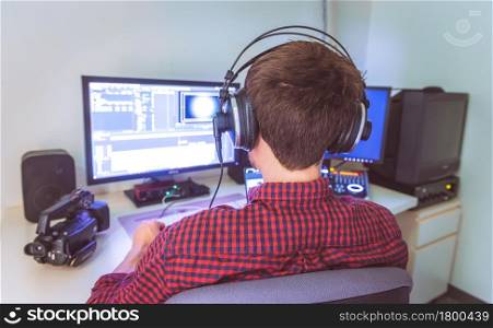 Close up of young Caucasian video editor in cutting room, monitors and the background