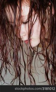 Close up of young Caucasian woman with long red wet hair.
