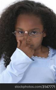 Close-up of young child pushing up her glasses.
