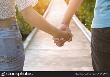 Close up of young couple Holding Hands while walking on walkway in natural parkland, Couple summer vacation travel