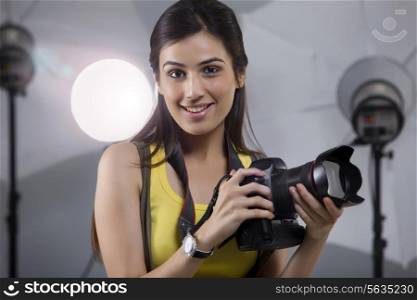 Close-up of young female photographer with digital camera in studio