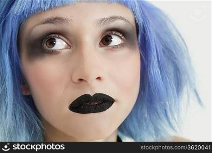 Close-up of young female punk with black lipstick, eye make-up and blue hair