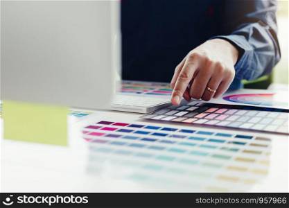 Close up of young graphic designer choosing a color from the palette in modern office.
