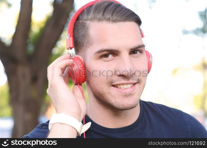 Close up of young handsome man with headphones in a park. Outdoors.
