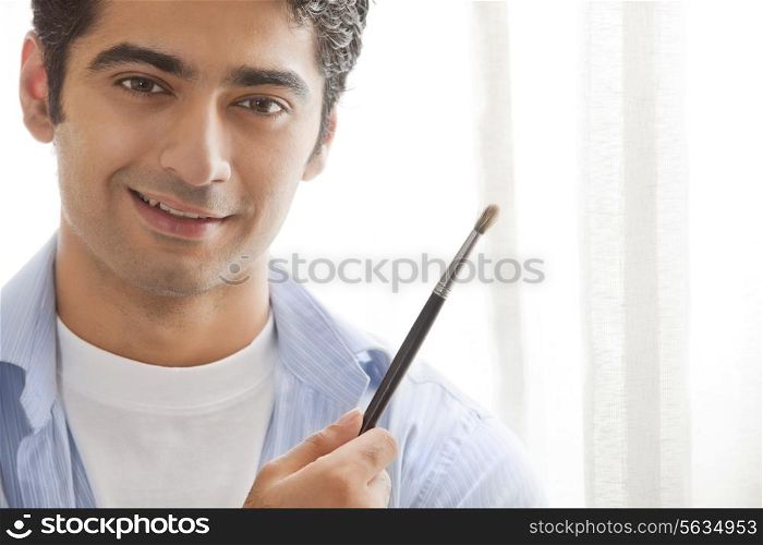 Close-up of young male artist holding paintbrush