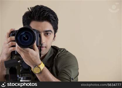 Close-up of young male photographer taking a photograph
