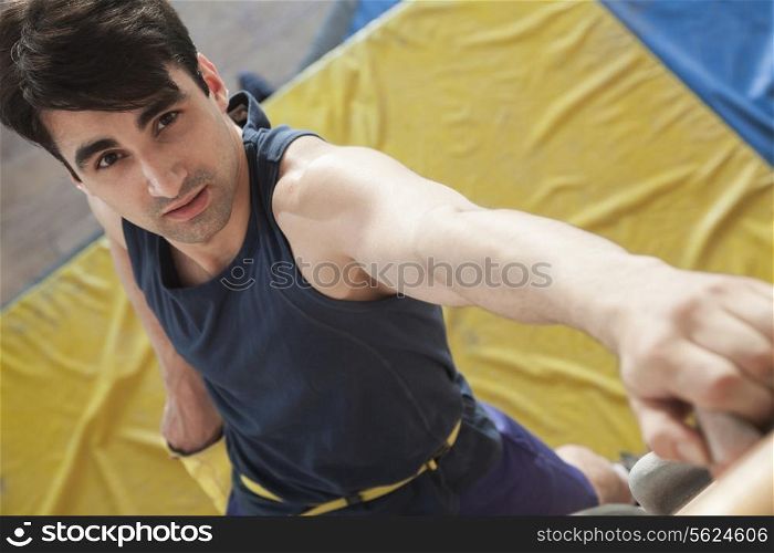 Close-up of young man climbing up a climbing wall in an indoor climbing gym, directly above