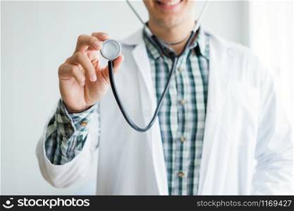 Close-up of Young man doctor therapeutic advising smiling face abstract blur with focus show holding stethoscope with in hospital background.