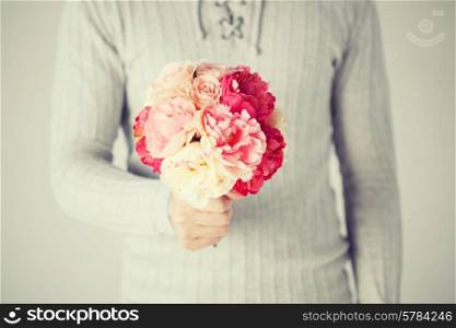close up of young man holding bouquet of flowers.