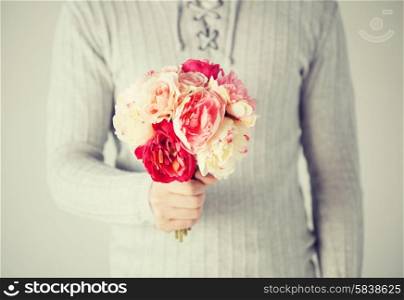 close up of young man holding bouquet of flowers.