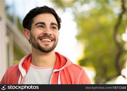 Close-up of young man smiling while standing outdoors at the street. Urban and lifestyle concept.. Close-up of young man smiling outdoors.