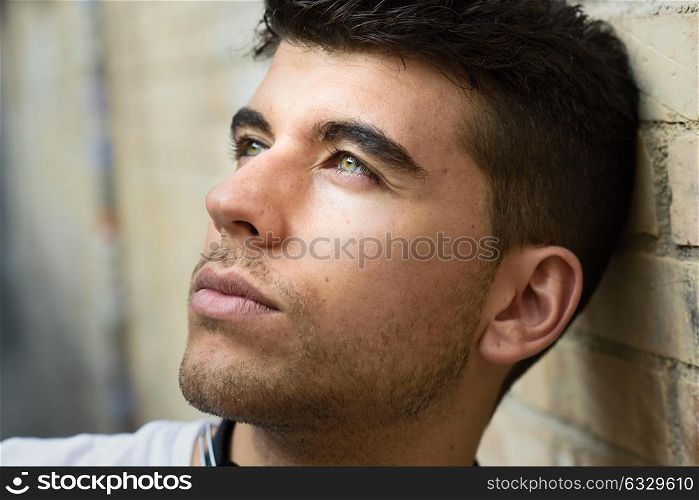 Close-up of young man with blue eyes in the street. Model of fashion in urban background