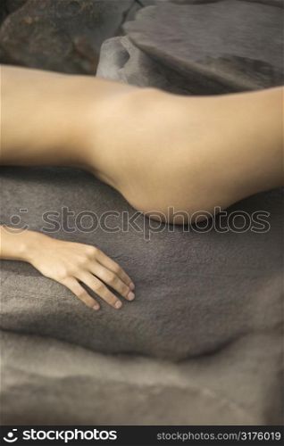 Close up of young nude Caucasian womans torso lying on rock.