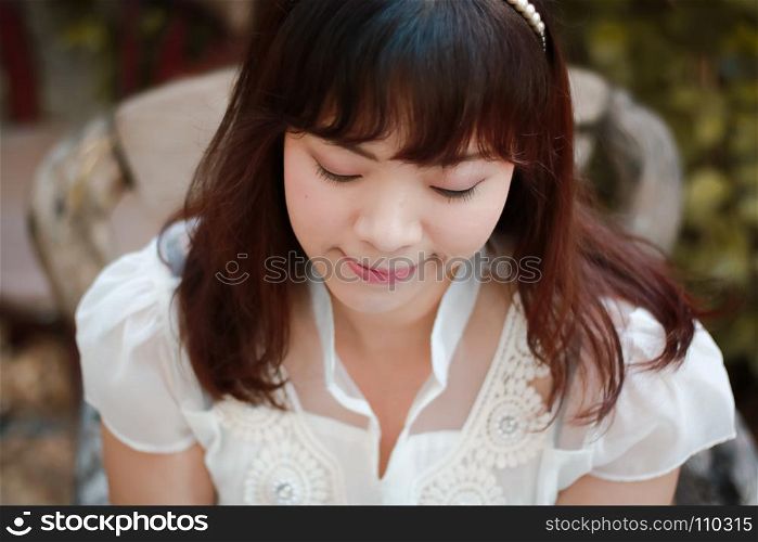 Close up of young pretty Asian woman in white dress with garden background.