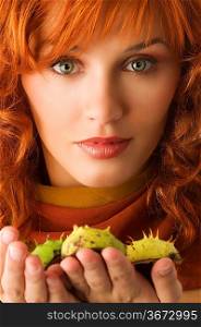 close up of young red haired woman with some wild chestnut in hands