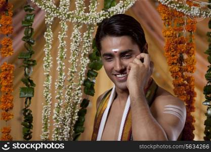 Close-up of young smiling groom having conversation on cell phone