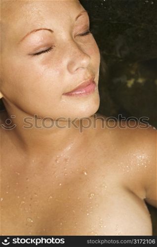 Close up of young topless Caucasian woman with eyes closed.