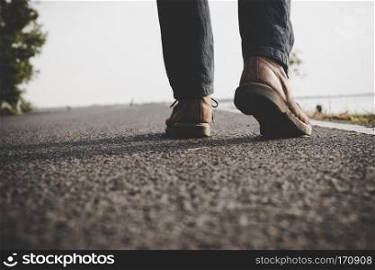 Close up of young tourist man walking on a countryside road.