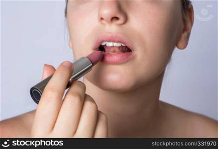 Close-up of young woman applying lipstick on studio.