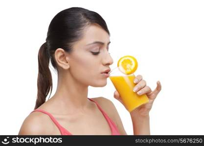 Close-up of young woman drinking orange juice over white background