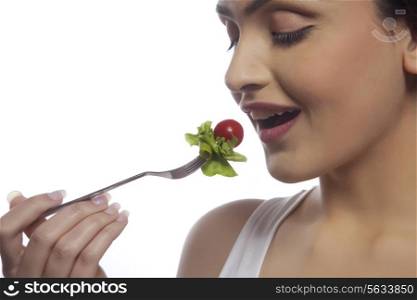 Close-up of young woman eating salad against white background