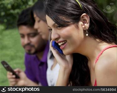 Close-up of young woman having conversation on phone with friend in background