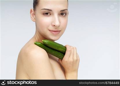 Close-up of young woman holding two cucumbers