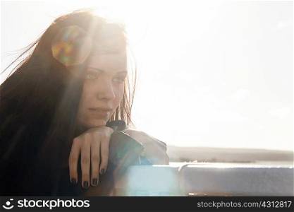 Close up of young woman leaning against fence