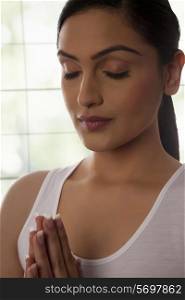 Close-up of young woman meditating against glass window