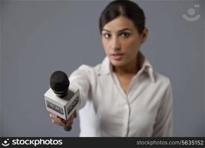 Close-up of young woman news reporter holding out microphone