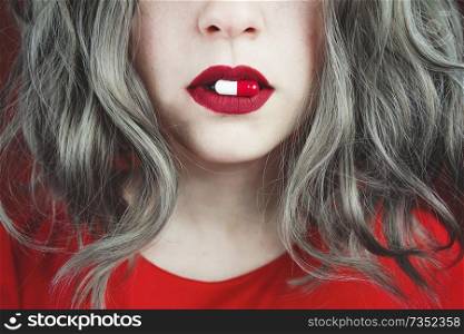 Close up of young woman’s lips holding a pill                               
