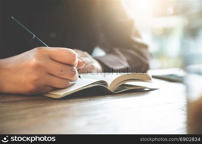 close up of young woman taking notes at home
