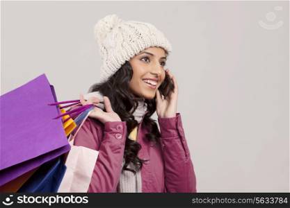 Close-up of young woman talking on cell phone and holding shopping bags