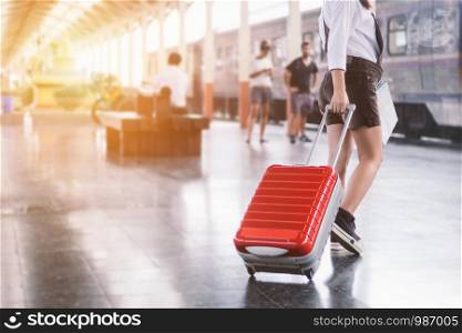 Close-up of young woman traveler carrying her trolley red bag and map in a train station.