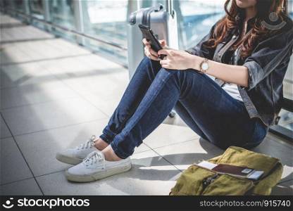 Close up of young woman with bag and suitcase luggage waiting for departure while sitting in airport lounge. Female traveler and tourist theme. High season and vacation concept. Relax and lifestyles