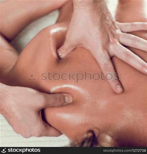 Close up of young woman with oiled skin having relaxing shoulders and back massage