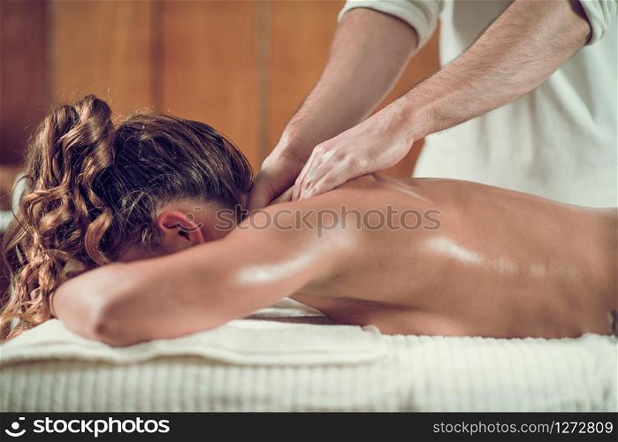 Close up of young woman with oiled skin having relaxing shoulders and neck massage