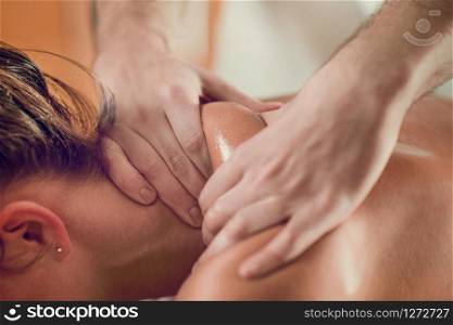 Close up of young woman with oiled skin having relaxing shoulders massage