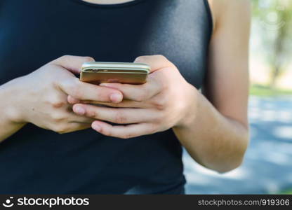 Close up of young women's hands holding smartphone and pointing with figer. Outdoors