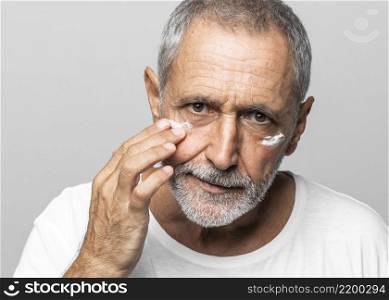 close up old man using face cream