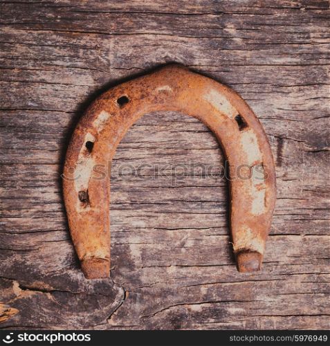 Close-up old rusty horseshoe on wooden background. Horseshoe for good luck