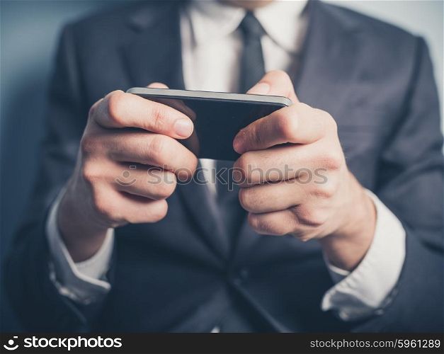 Close up on a businessman&rsquo;s hands as he is using a smartphone